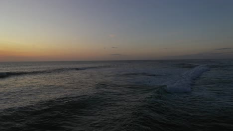 aerial shot of waves with moody-looking sunset