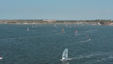 drone - aerial shot of many surfers on a blue, wavy and windy sea on a sunny day with white clouds on a island, zeeland, netherlands, 30p