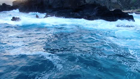 ハワイの暗い日没時に海岸に荒波が打ち寄せる中、無人機が海の岩に押し寄せる