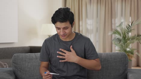 sick indian man measuring fever using thermometer