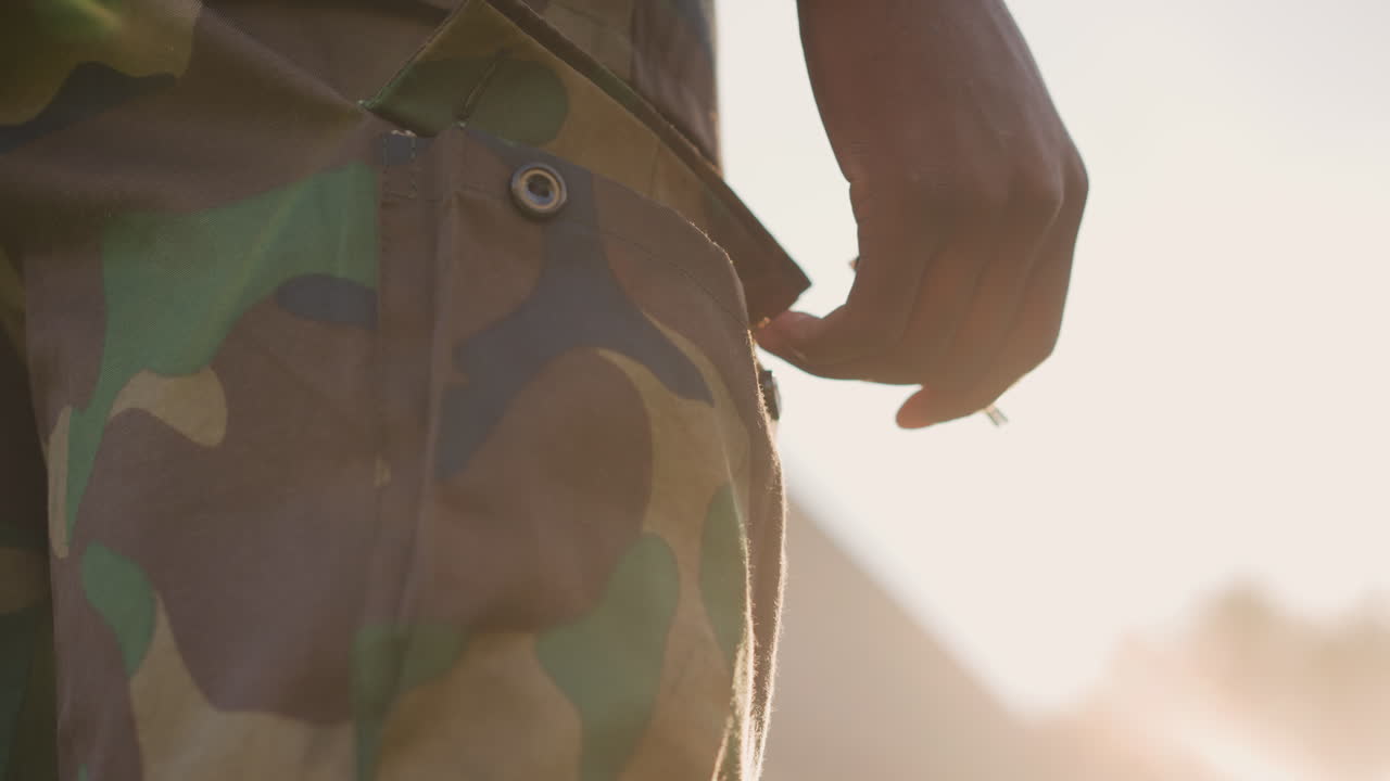 Soldato silenzioso al tramonto, il crepuscolo cala sul soldato pensieroso in tenuta militare, silenzioso e riflessivo. Veterano esperto vestito in tenuta mimetica, in contemplativo silenzio con il bagliore del tramonto sullo sfondo