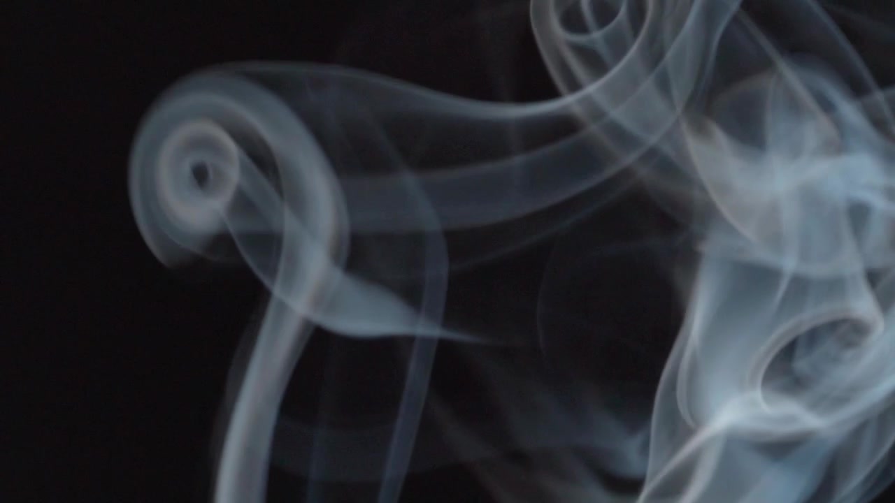 Vista macro di fumo di incenso vorticoso che forma motivi astratti su sfondo scuro, evidenziando il movimento fluido, le forme alla deriva e i dettagli atmosferici.