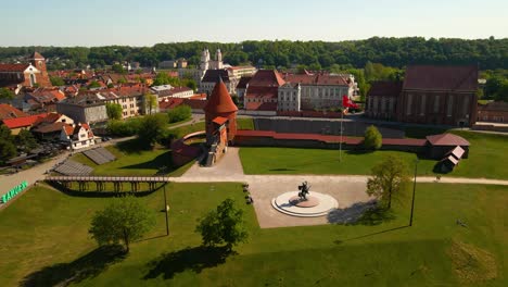 Drone-shot-of-the-historic-old-red-brick-Kaunas-Castle-with-Vytis-statue-in-Kaunas-old-town,-Lithuania-on-a-sunny-day,-zoom-in-shot