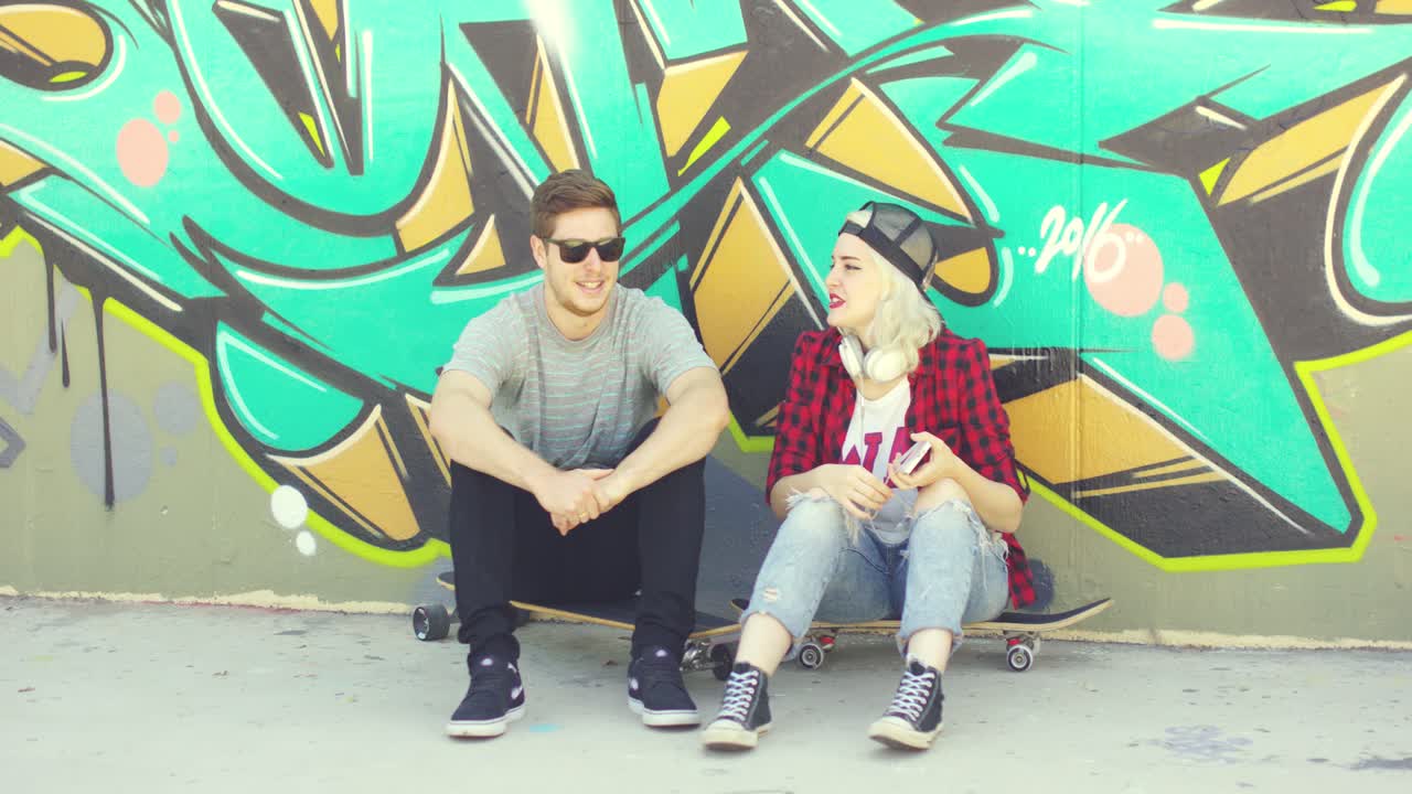 joven pareja urbana hipster relajándose en una acera