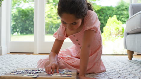 Chica-En-Casa-Sentada-En-El-Suelo-En-El-Salón-Haciendo-Rompecabezas