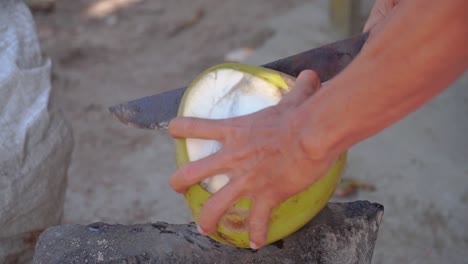 hand of a man peel green young coconut using machete to make young coconut drink