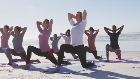 Multiethnische-Gruppe-Von-Frauen,-Die-Yoga-Position-Am-Strand-Und-Im-Hintergrund-Des-Blauen-Himmels-Machen