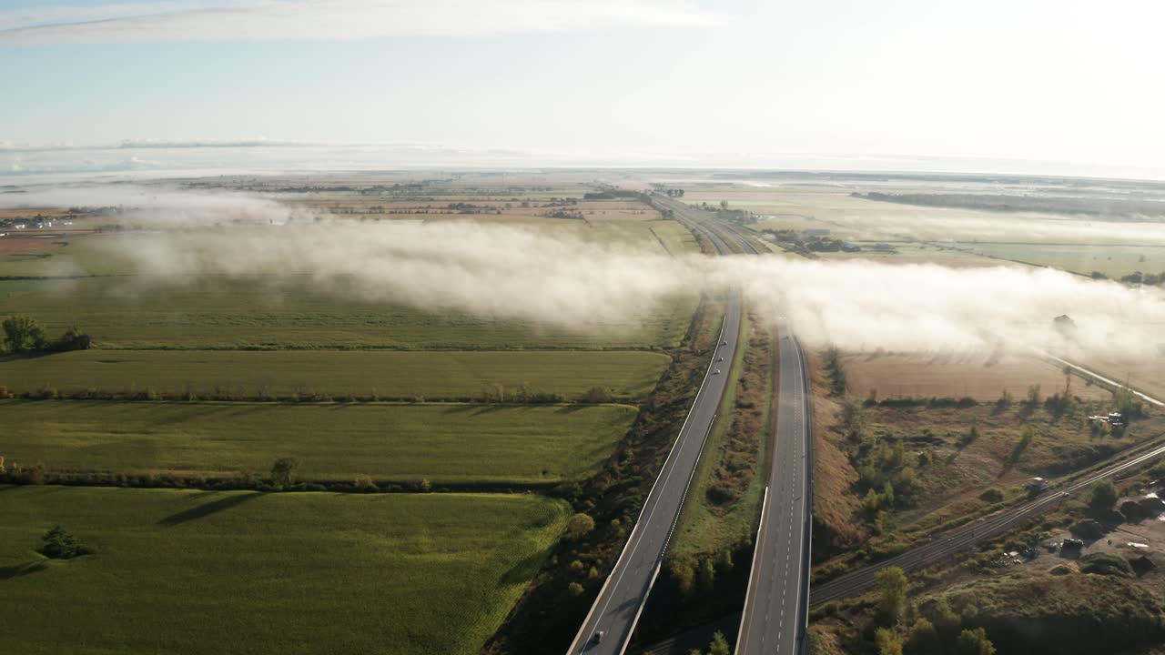 교통량이 적고 아침 햇살이 비치는 주간 고속도로의 고르지 못한 짙은 안개