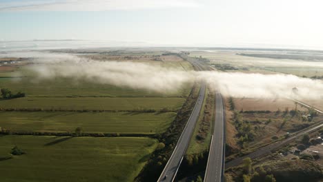 Fleckiger-Dichter-Nebel-über-Der-Autobahn-Mit-Leichtem-Verkehr-Und-Morgensonne