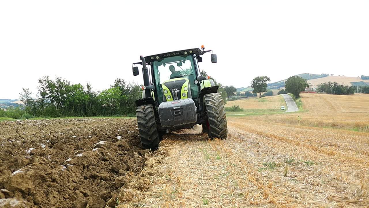 front view of heavy agricultural vehicle moves on the land that has just been harvested