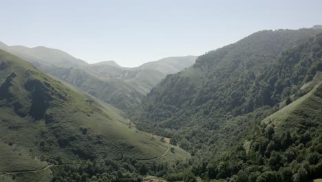 flyover grassy mountain valley slopes in french pyrenees, small road