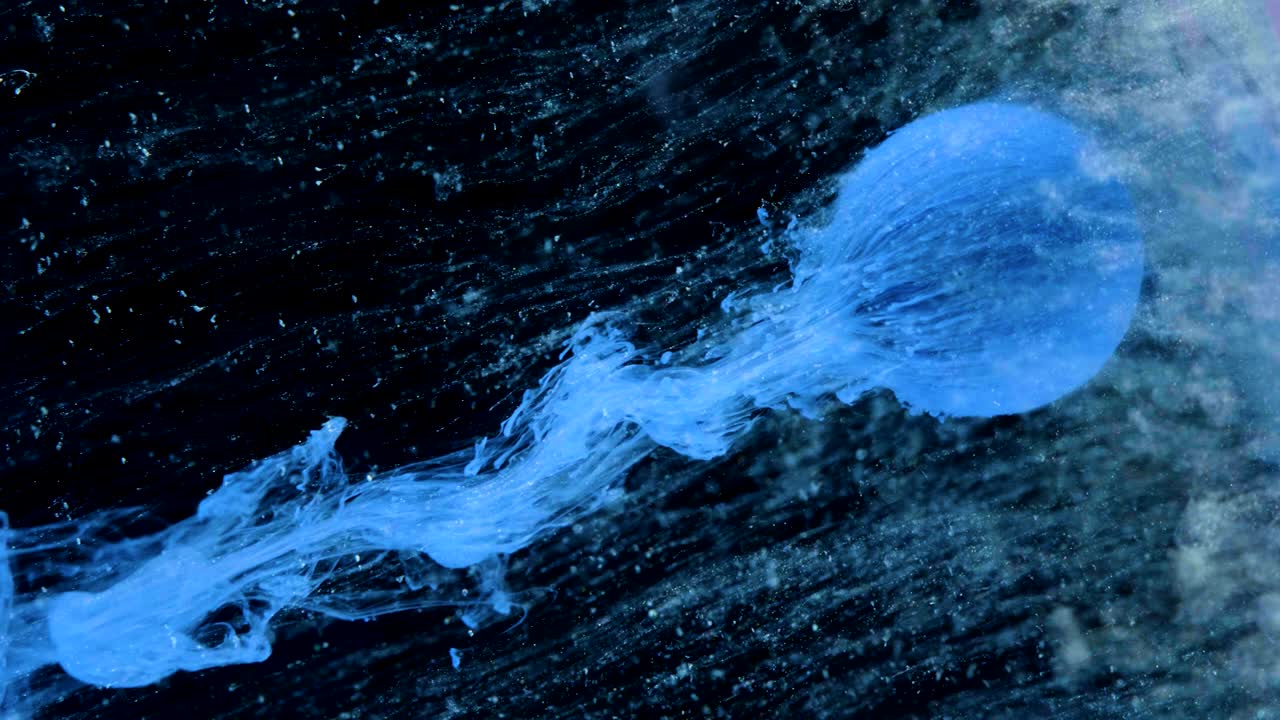 다채로운 잉크 페인트가 천천히 공에서 흘러나옵니다.