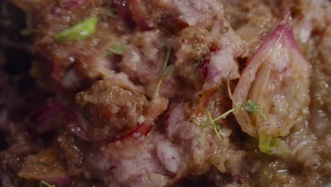 mixing alla genovese sauce with beef shank, onion slices, celery and spices inside a deep cooking pot