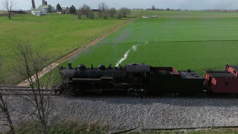 a vintage steam train chugs along the tracks, surrounded by vibrant green fields and trees under a clear sky. its whistle pierces the calm, evoking nostalgia.