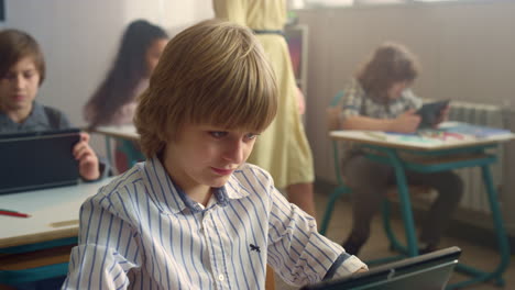 Boy-looking-on-screen-of-digital-tablet-during-lesson.-Student-learning-with-pad