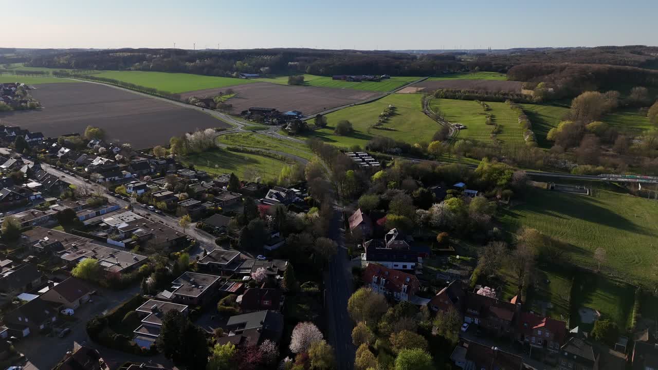 Housing area with single Family houses and solar panels on roof. Tree-lined trees during sunset time in spring season. Quiet agricultural farm fields on hills in USA. Aerial forward wide shot. PA,USA