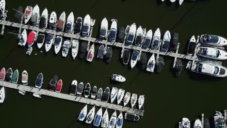 static lookdown aerial drone view over boat moorings and colourful yachts at bowness marina on lake winderemere with small boat moving through the scene on sunny summer morning