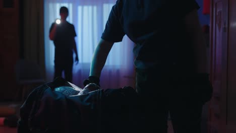 closeup shot of black sport bag police woman takes out the illegal objects man with flashlight in crime scene creative concept closeup shot of black sport bag with illegal stuff police woman opens it takes out gun money and pack of drugs man officer with flashlight standing in the background