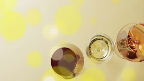 composite of glasses of white, rose and red wine over yellow spots on yellow background