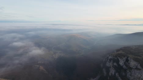 vista aérea de un paisaje montañoso brumoso con valles visibles y crestas boscosas bajo un cielo nublado suave