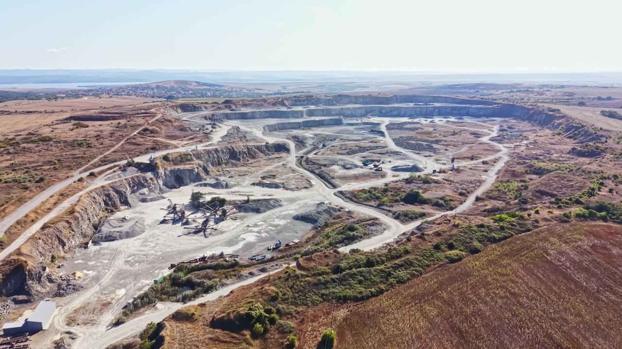 Granite quarry shows operations, equipment, and landscape from above during daylight hours