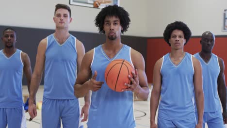 diverse male basketball team with ball at training session on indoor court, in slow motion