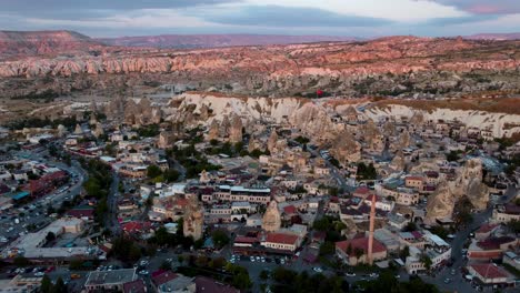 goreme stone buildings glow under sunset skies amid cappadocia rock formations, urban buildings and nature mix together