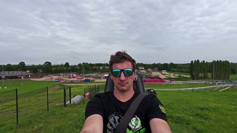 a selfie shot of a man admiring the surroundings as he rides on a mini roller coaster at a park