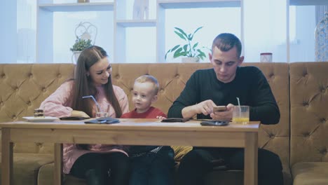 Mutter-Und-Kind-Halten-Blauen-Plastikstrohhalm-In-Der-Hand-Und-Sitzen-Auf-Einem-Braunen-Sofa