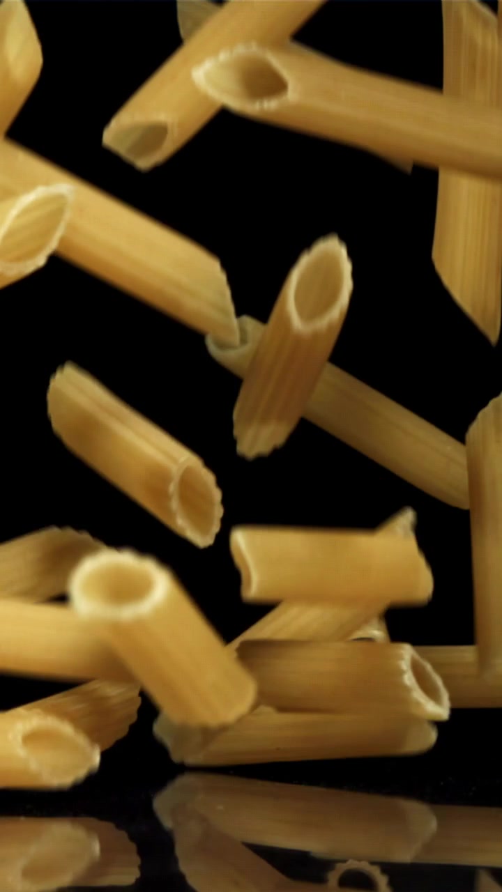 Pasta penne che cade al rallentatore su sfondo nero