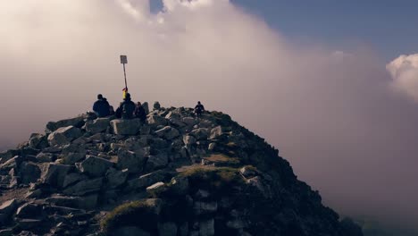 amplia toma de drones girando alrededor de excursionistas sentados en la cima de una montaña
