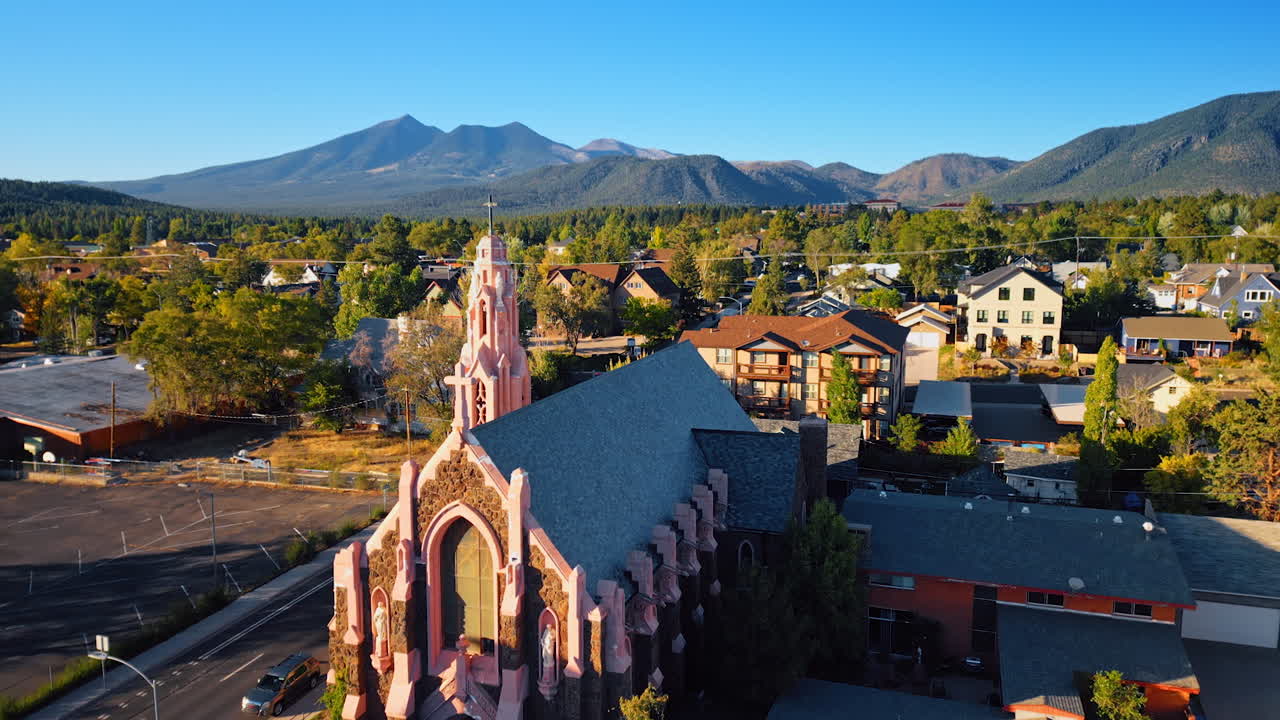 Rising over the church of Nativity in Flagstaff, Arizona, USA. Revealing view on the green scenery of city on sunny day. Beautiful mountains at backdrop