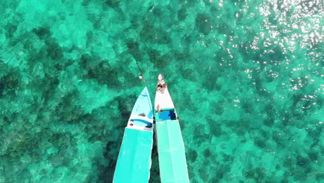 aerial view of traditional boats on crystal clear turquoise water in indonesia