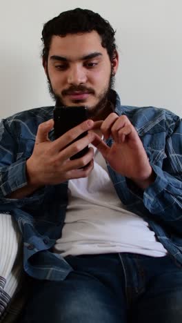 relaxed young man using smartphone on sofa