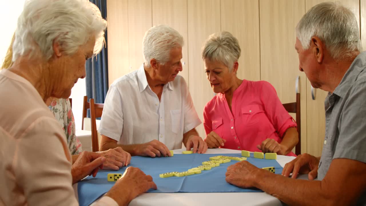 Senior friends talking while playing dominos