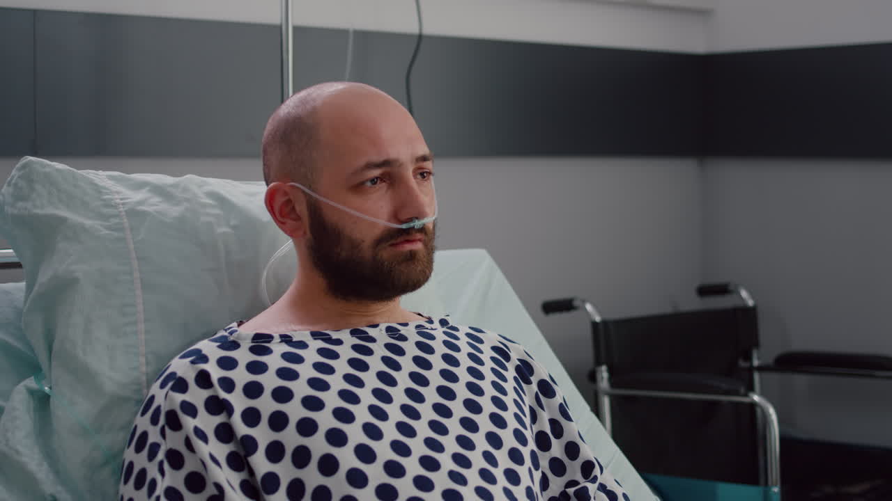 Uomo malato triste con il tubo nasale dell'ossigeno che riposa nel cattivo che esamina la macchina fotografica
