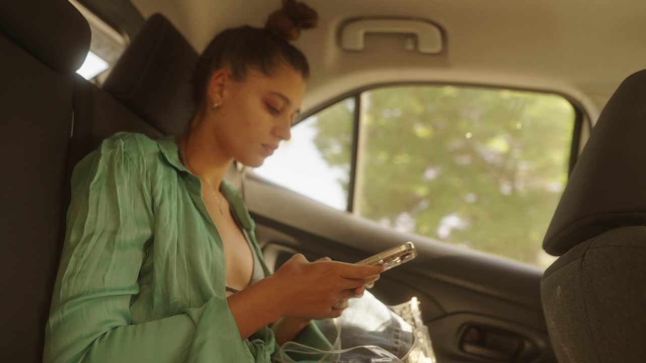 A woman uses her phone in the back of a car