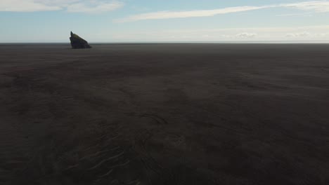 black sand desert with rocky outcrop