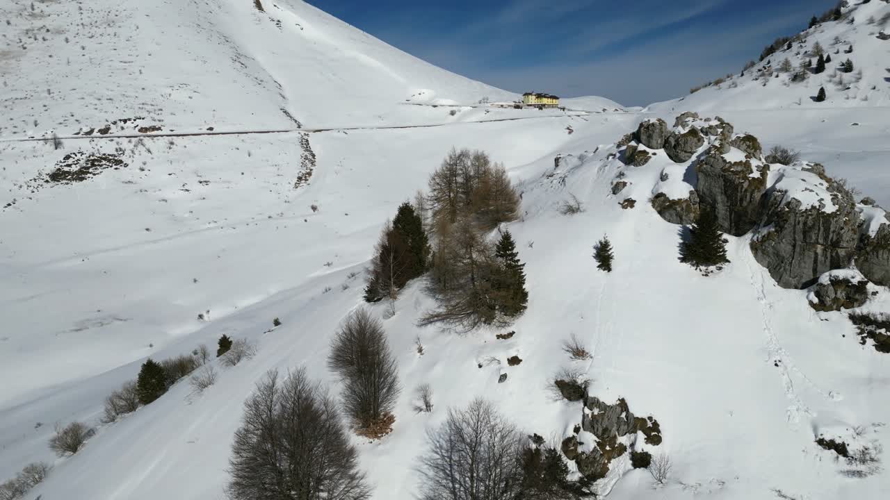 Riprese aeree con drone del Monte Altissimo, Italia: paesaggio alpino innevato con creste rocciose e alberi ghiacciati sotto la chiara luce invernale. Ideale per progetti su natura, montagna e paesaggi