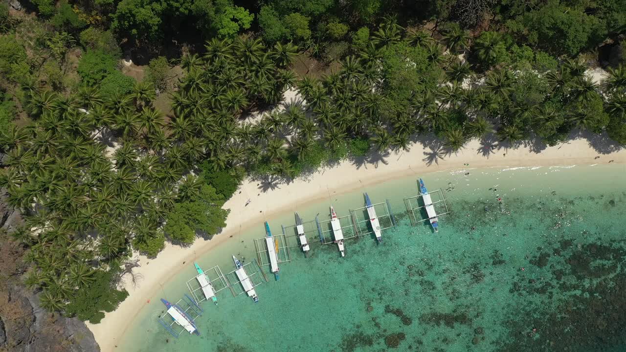 Drone flight over El Nido in the Philippines beaches and limestone cliffs, showing longtail boats, emerald green sea, clear waters, amazing beaches