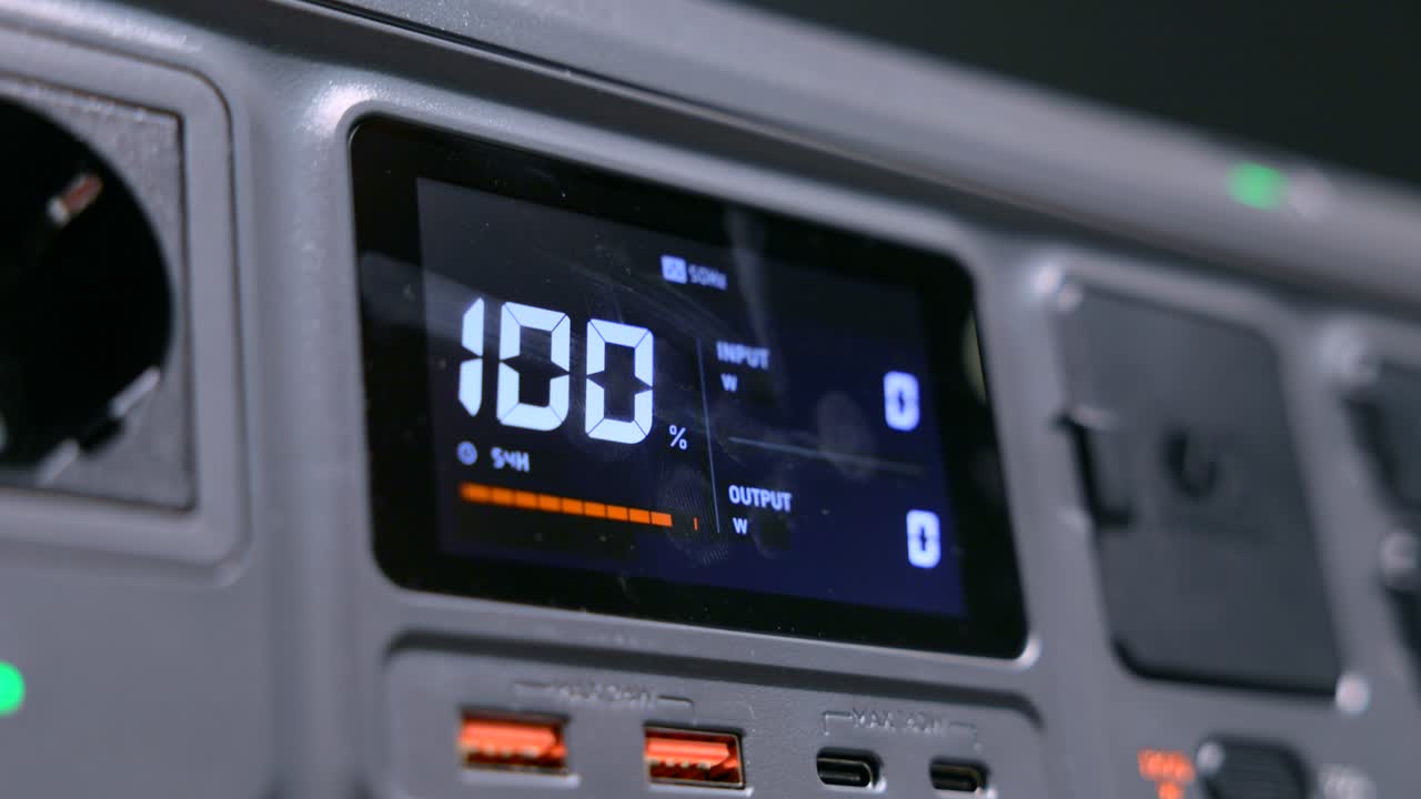 Detailed view of a portable power station showing USB ports and a 100% battery status on the LCD display, ideal for outdoor use.