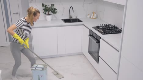 the work of a cleaning company a woman worker cleans the house wet cleaning with a mop