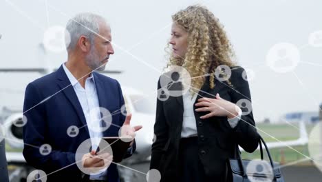 Animation-Von-Netzwerksymbolen-über-Kaukasischen-Geschäftsfrauen-Und-Geschäftsleuten,-Die-Sich-Am-Flughafen-Unterhalten