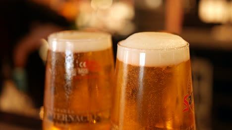 fizzy beer larger in two pint glasses on a bar in a pub