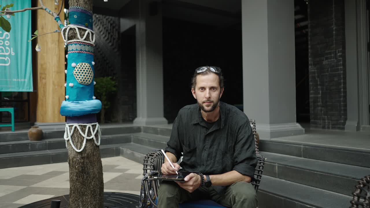 A man drawing on a tablet outdoors