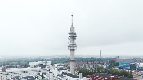 Toma-Aérea-Amplia-De-Una-Sombría-Torre-De-Enlace-De-Radio-Y-Televisión-De-Hormigón-Industrial-En-Pasila,-Helsinki,-Finlandia,-En-Un-Día-Brillante-Y-Brumoso