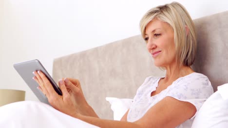 Happy-woman-using-tablet-in-bed