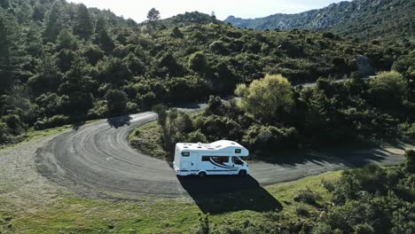 aerial drone fly above white camper van, rv driving uphill green mountain valley of southern france, summer skyline