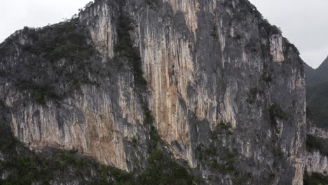 dramatic karst mountain rock face, rugged texture, rising aerial view