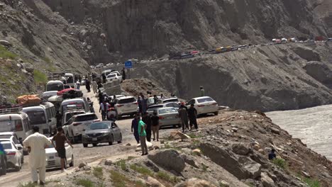 cars passing back the road after a traffic blockade, caused by land sliding in chilas region, pakistan, static shot, people and cars, copy space